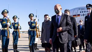 Lors de son accueil à l’aéroport, le chancelier Olaf Scholz s’avance au milieu d’une haie d’honneur chinoise.