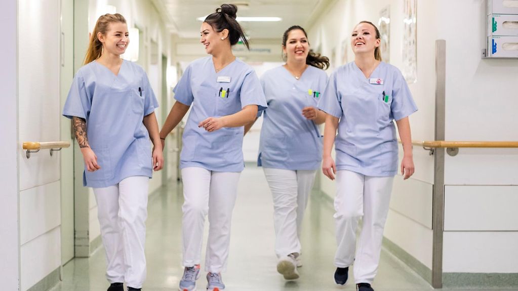 Vier junge Krankenpflegerinnen auf einem Krankenhausflur.