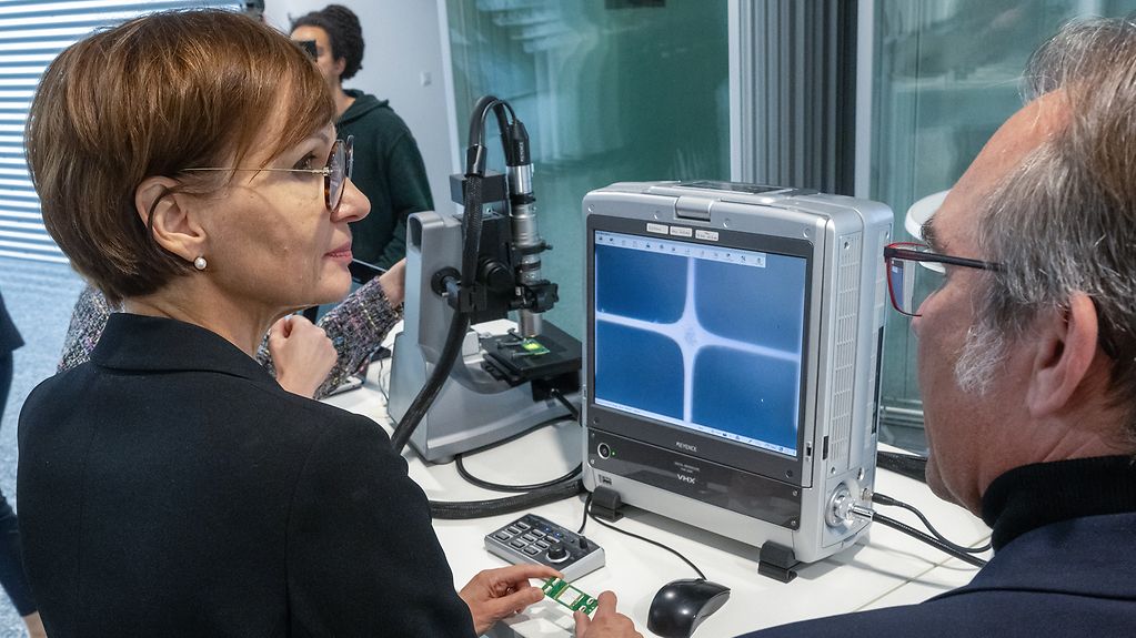 Bundesforschungsministerin Bettina Stark-Watzinger erkundigt sich über das neue Forschungszentrum in Jena. Im Hintergrund ein spezieller Monitor mit lichtbasierter Technologie.