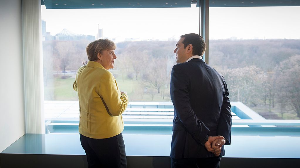 Angela Merkel and Alexis Tsipras stand at a window in the Federal Chancellery.