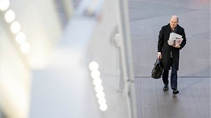 Bundeskanzler Olaf Scholz geht auf dem Flughafen mit einem Pack Zeitungen unter dem Arm zum Flugzeug.