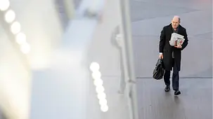 Bundeskanzler Olaf Scholz geht auf dem Flughafen mit einem Pack Zeitungen unter dem Arm zum Flugzeug.