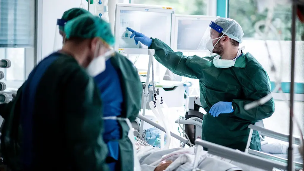 Mitarbeiter der Pflege in Schutzkleidung behandeln einen Patienten auf der Intensivstation.