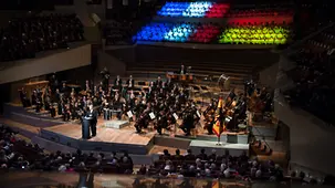 Blick in die Philharmonie. Im Hintergrund sind die deutsche und französische Flagge auf Jugendliche beider Länder projiziert.
