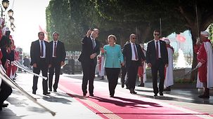Chancellor Angela Merkel walks beside Tunisia's Prime Minister Youssef Chahed.