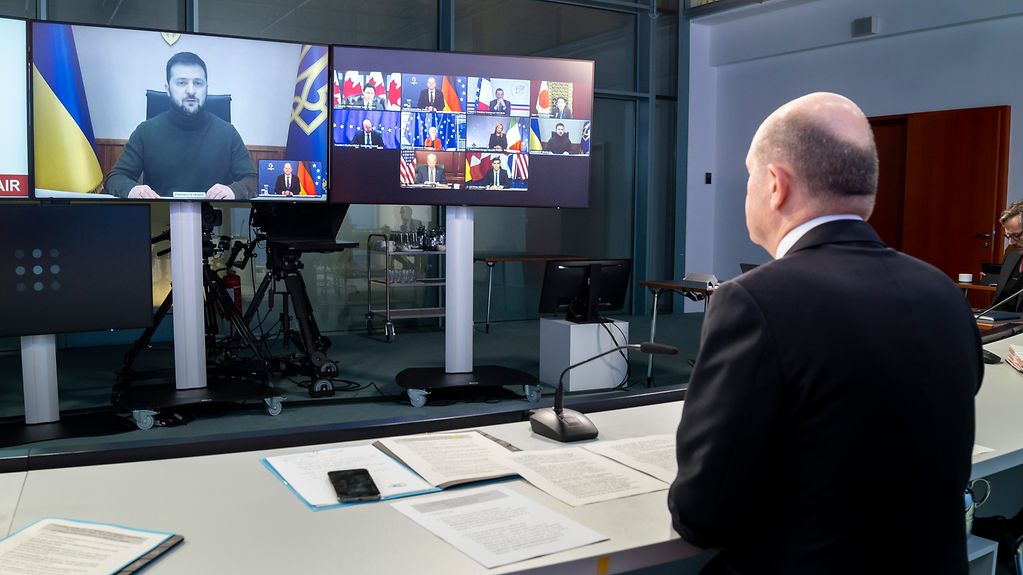 Sur la photo, on voit le chancelier Olaf Scholz devant un écran où le président ukrainien Volodymyr Zelensky est en train de parler.
