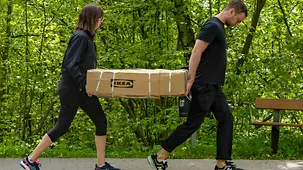 Ein junges Paar trägt gemeinsam einen Karton von Ikea.