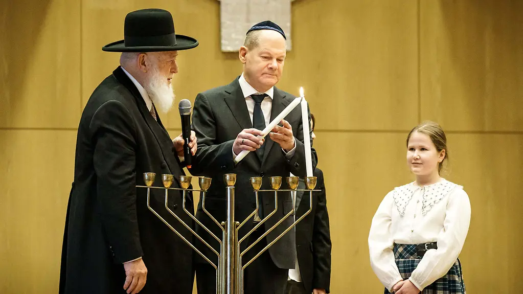 Bundeskanzler Olaf Scholz entzündet eine Kerze eines Chanukka-Leuchters.