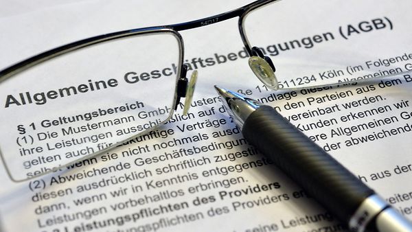 Brille und Kugelschreiben auf einem Dokument mit der Überschrift Allgemeine Geschäftsbedingungen