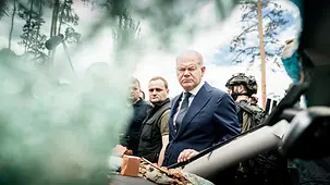 Bundeskanzler Olaf Scholz bei einem Rundgang im zerstörten Stadtzentrum (vor einem zerbombten Auto)
