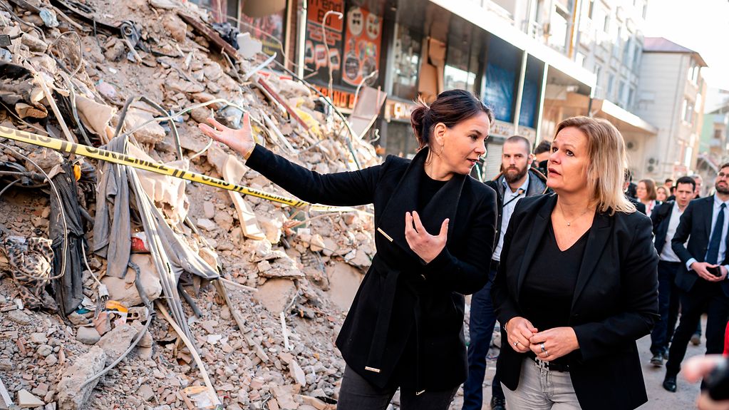 Außenministerin Annalena Baerbock und Bundesinnenministerin Nancy Faeser stehen vor einem Schutthaufen in der vom Erdbeben schwer getroffene Stadt Pazarcik in der Region Kahramanmaras.