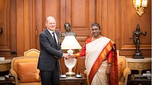 Bundeskanzler Scholz und die indischen Präsidentin Droupadi Murmu reichen sich die Hand.