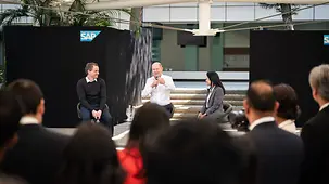 Der Bundeskanzler sitzt auf einem Podium und diskutierte mit dem Publikum.