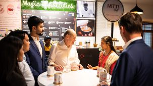 Bundeskanzler Scholz bei einem Kaffee im Gespräche mit jungen Inderinnen und Indern.