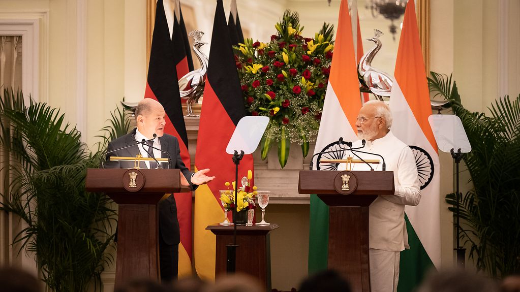 Le chancelier fédéral Olaf Scholz et le premier ministre indien Narendra Modi tiennent une conférence de presse, debout à la tribune, devant les drapeaux des deux pays.