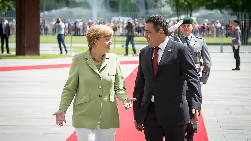 Federal Chancellor Angela Merkel and the Prime Minister of Tunisia, Mehdi Jomaâ, walking together during the welcoming ceremony with military honours.