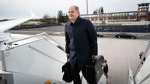 Bundeskanzler Olaf Scholz betritt ein Flugzeug.