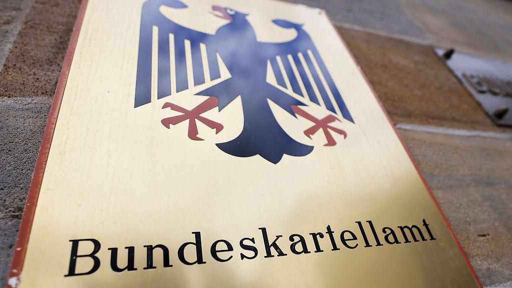 Ein Schild mit Bundesadler hängt vor dem Bundeskartellamt in Bonn.