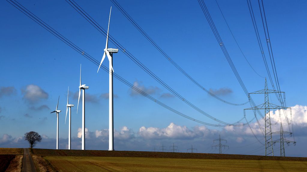 Strommasten und Windräder stehen auf einem Feld im Kreis Düren (Nordrhein-Westfalen).