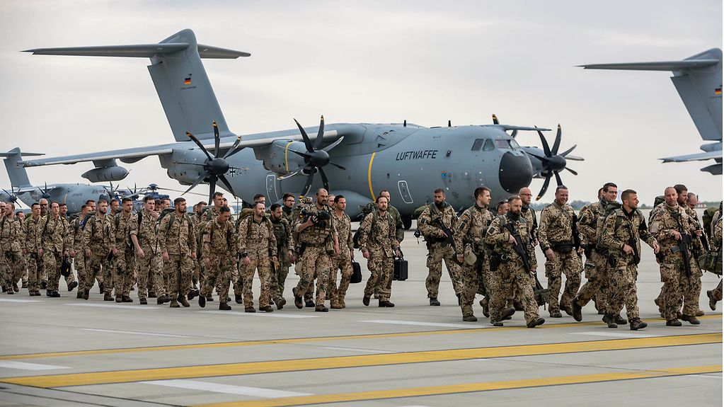 Soldaten gehen vor einem Flugzeug der Luftwaffe.