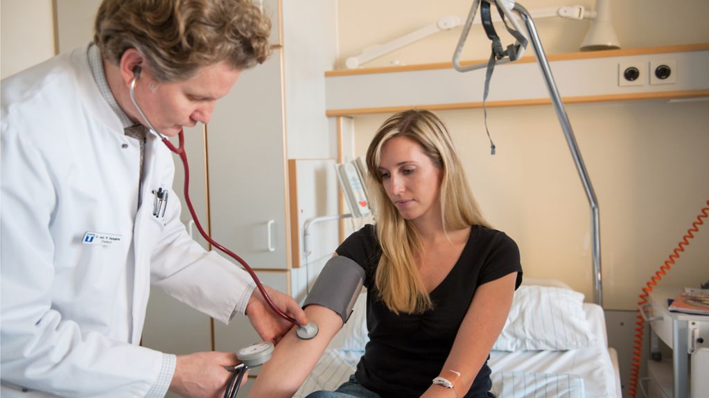 Arzt misst Blutdruck von Patientin 