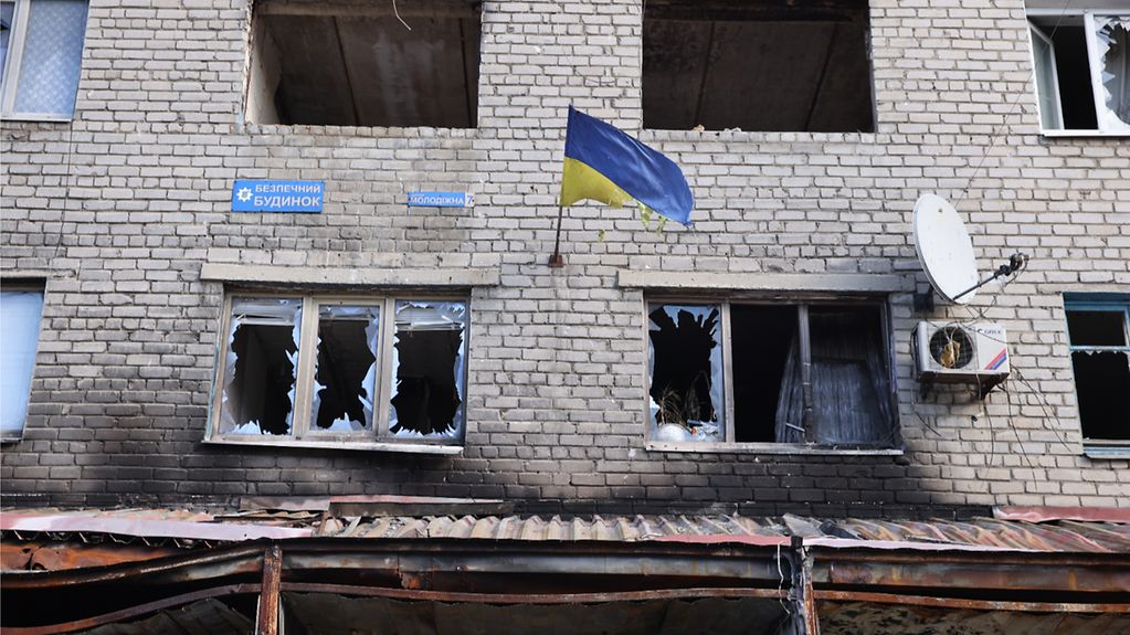 A Ukrainian flag on the side of a house destroyed in the war.