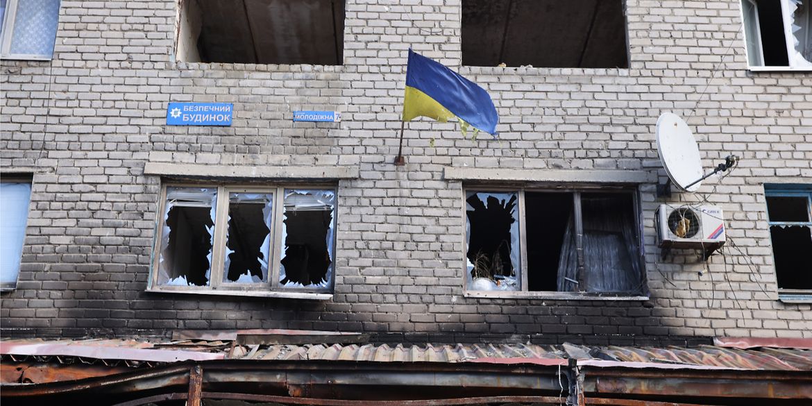 A Ukrainian flag on the side of a house destroyed in the war.