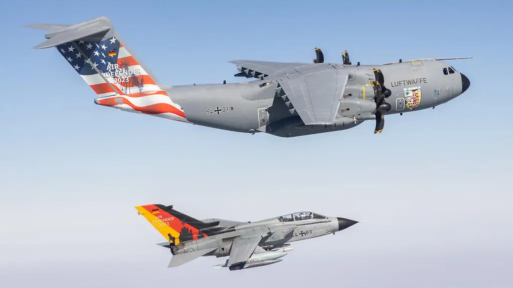 An Airbus A400M transport aircraft and an Air Force Tornado fighter jet painted with the German flag and with the US flag at the rear are flying next to each other.