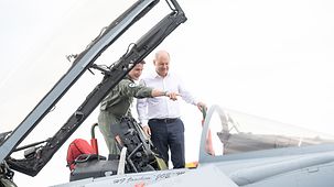 Bundeskanzler Olaf Scholz mit einem Piloten an einem Eurofighter