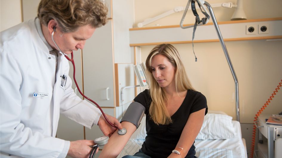 Ein Arzt misst den Blut-Druck von einer Patientin 