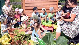 Vvier- und fünfjährigen Kinder singen mit den Erzieherinnen im Gemüsebeet der Kita