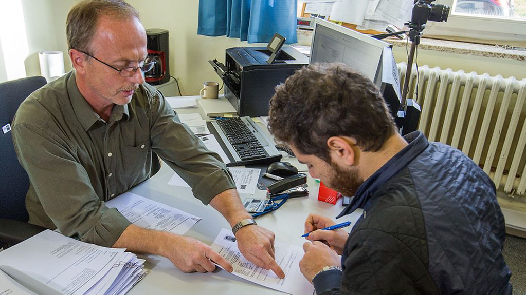 Flüchtling bei der Registrierung mit Mitarbeiter einer Behörde