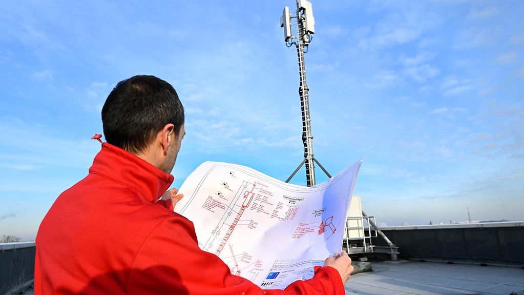 Ein Techniker steht vor einem neu errichteten 5G-Mobilfunkmast.
