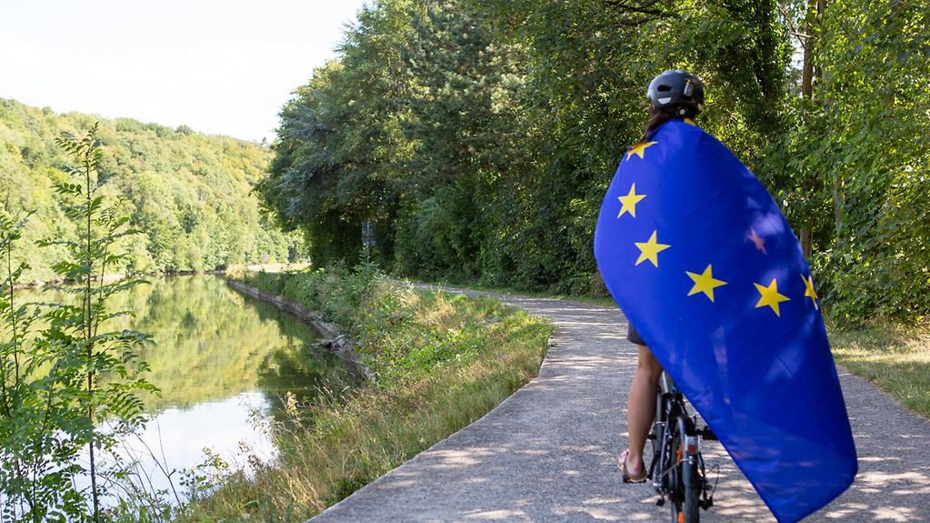 Eine Frau auf einem Fahrrad mit der europäischen Flagge