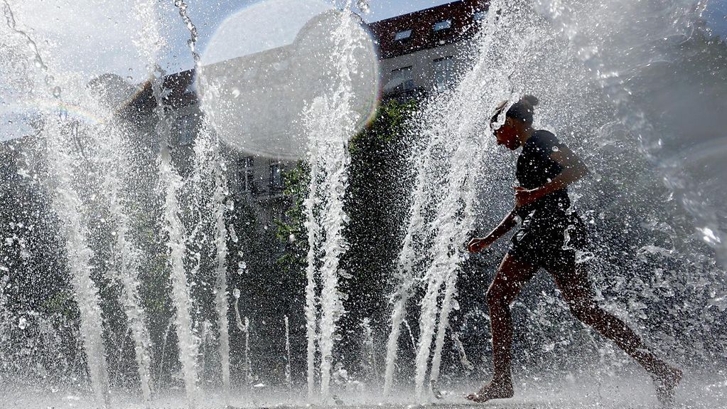 Ein Mädchen spielt in einer Fontaine in Berlin
