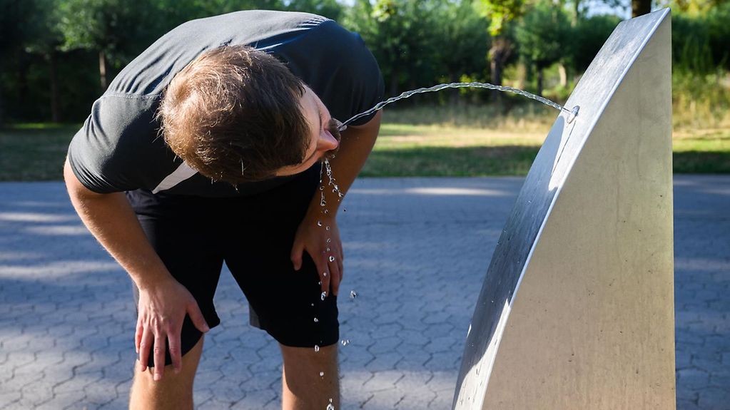 Ein Sportler trinkt Wasser an einem öffentlichen Trinkwasserspender.