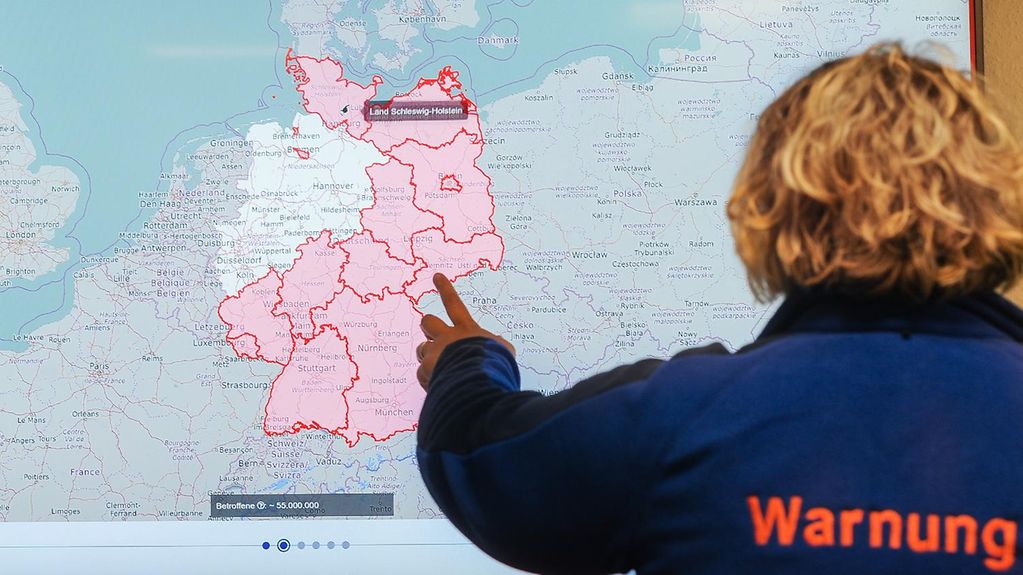 Foto zeigt eine Mitarbeiterin des BBK mit einre Landkarte von Deutschland.