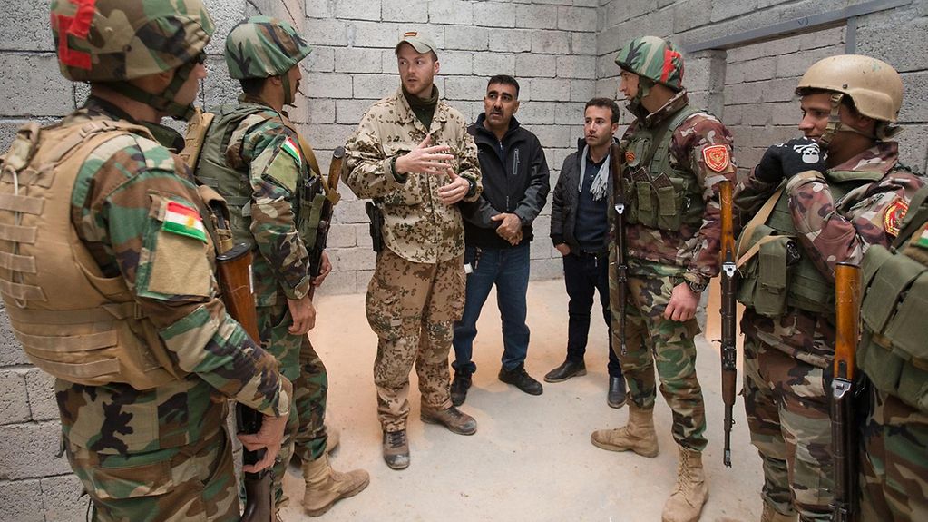 An interpreter helping a German trainer to explain the objective of a military exercise in Iraq.