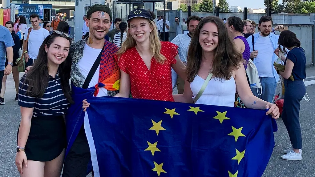 Vier junge Leute stehen zusammen und halten eine EU-Flaggte.