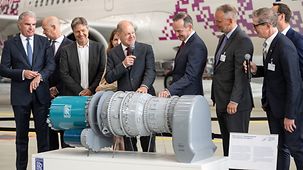 Bundeskanzler Olaf Scholz vor einem Konzept des Water-Enhanced Turbofan (WET) auf der Nationalen Luftfahrtmesse in Hamburg.