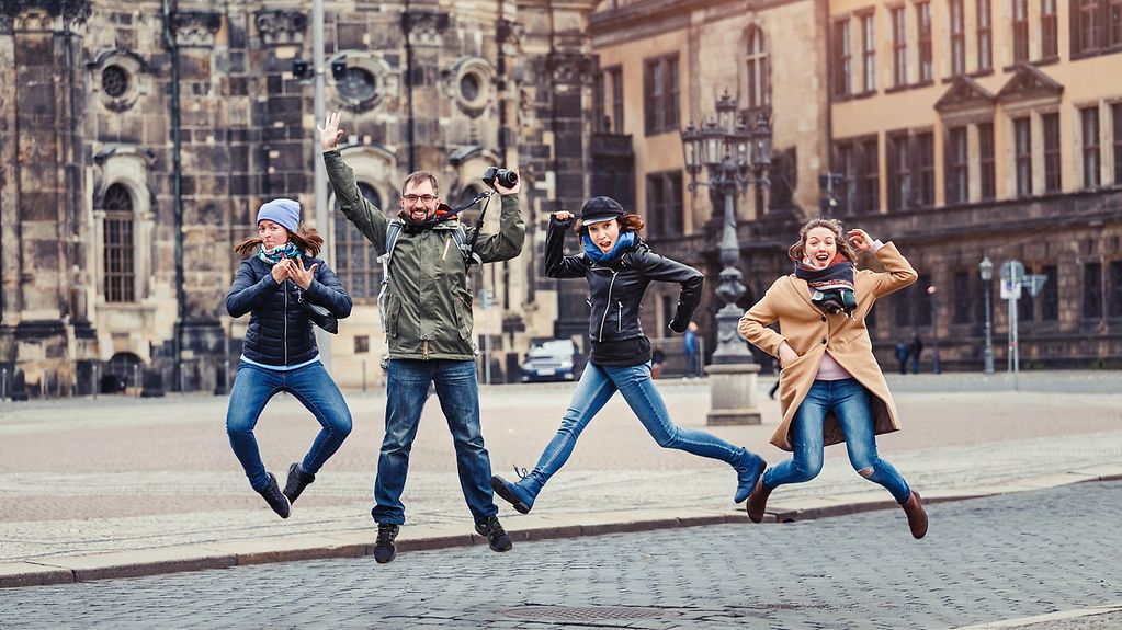 Eine Gruppe glücklicher Freunde springt in der Altstadtstraße in der Nähe des Schlosses in Dresden.