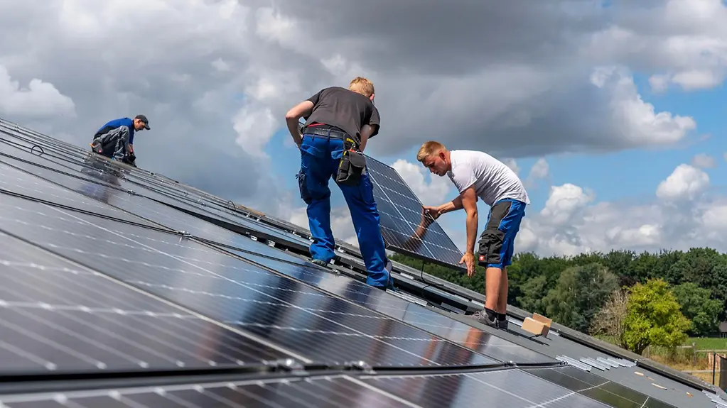 Auf dem Dach einer Scheune werden Solarmodule installiert.
