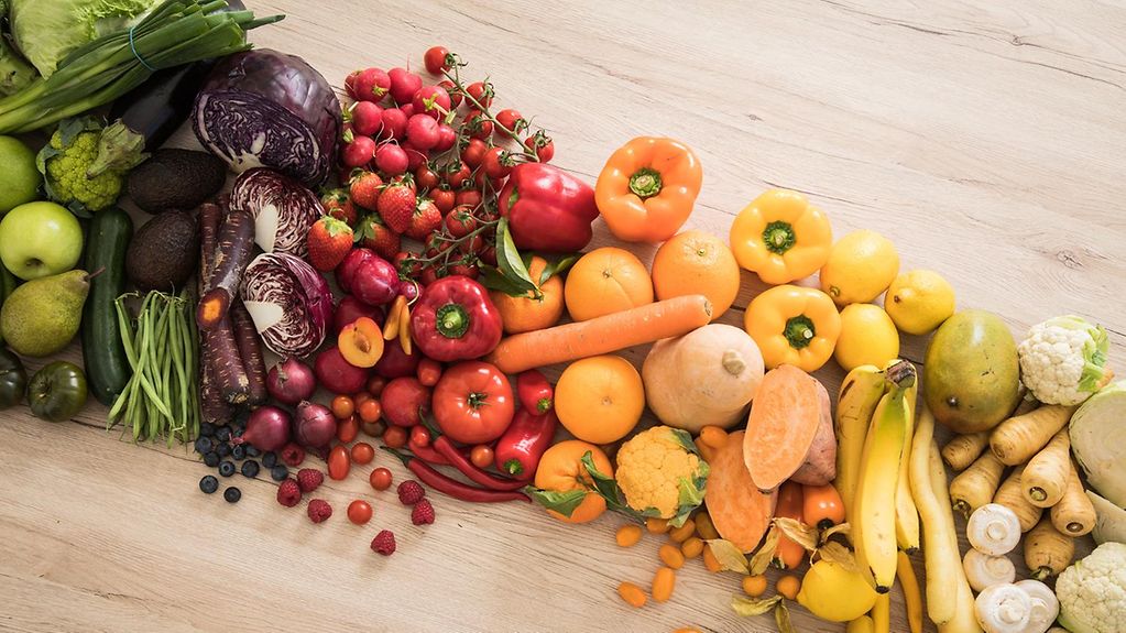 Obst und Gemüse liegt nach Farben sortiert auf einem Tisch.