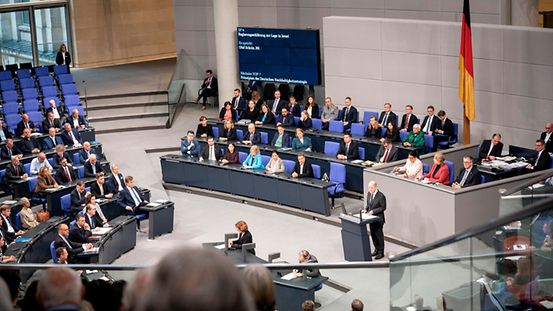 Bundeskanzler Olaf Scholz steht am Rednerpult im Bundestag. Mitglieder vom Bundestag sitzen auf ihren Plätzen und hören Olaf Scholz zu.