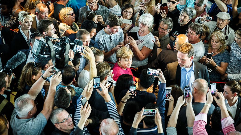 Bundeskanzlerin Angela Merkel wird beim traditionellen Rundgang am Tag der offenen Tür von Besuchern umringt.