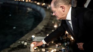 Bundeskanzler Olaf Scholz stellt eine Kerze ab.