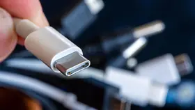 Ein Ladekabel mit USB-C-Stecker wird neben einem Bündel unterschiedlicher Anschlusskabel gehalten. 
