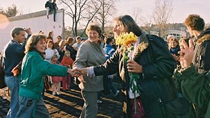 People in West Berlin welcome East Germans with flowers.