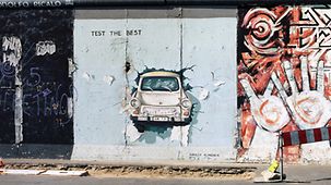 Image of a Trabant breaking through the Wall painted on a Wall section in the East Side Gallery in Berlin