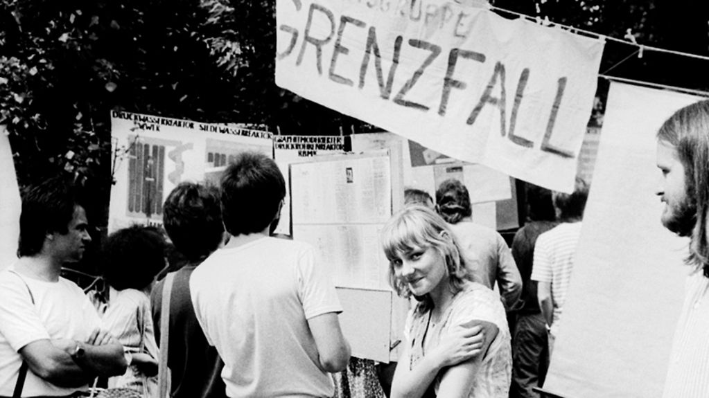 Stand der "Initiative für Frieden und Menschenrechte" auf der Friedenswerkstatt der Berliner Erlöserkirche am 29.6.1986. Im Hintergrund: Transparent mit Aufschrift Arbeitsgruppe Grenzfall